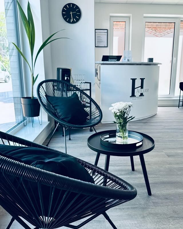 Wartebereich mit Sessel und Empfangstresen mit dem H des Haar Ateliers